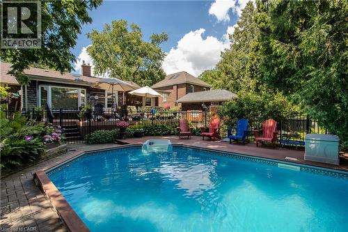 In-ground swimming pool with a surrounding dark wood-finish deck and brick paver accents - 569 Locust Street, Burlington, ON - Outdoor With In Ground Pool With Deck Patio Veranda With Backyard
