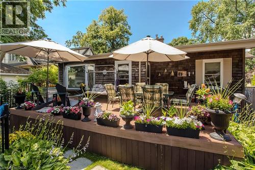 Expansive outdoor deck featuring wood-finish flooring, two outdoor umbrellas, and a surrounding privacy railing - 569 Locust Street, Burlington, ON - Outdoor With Deck Patio Veranda