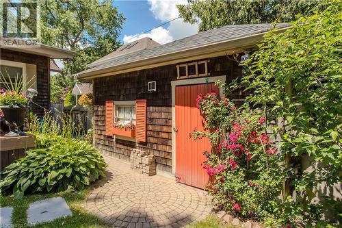 Storage shed with wood shake siding, a vibrant red door, and a window box with red shutters - 569 Locust Street, Burlington, ON - Outdoor With Deck Patio Veranda