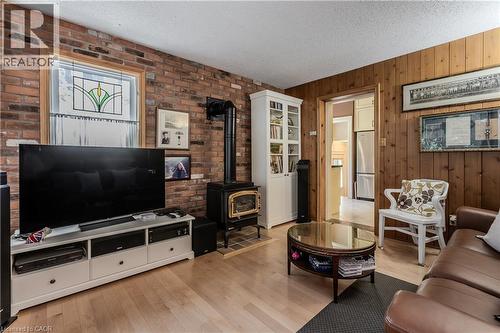 Living space featuring a prominent brick accent wall, a cast iron wood stove, and light wood-finish flooring - 569 Locust Street, Burlington, ON - Indoor Photo Showing Living Room