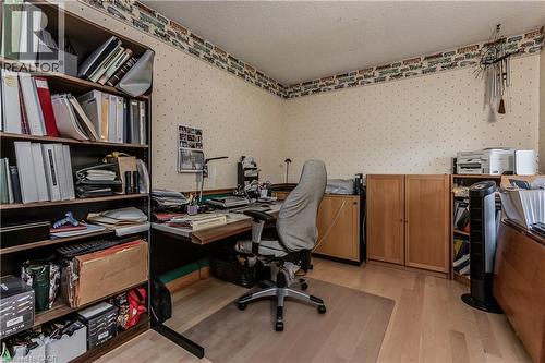 Room featuring light wood-finish flooring, textured white ceiling, built-in shelving, and pale patterned wallpaper with a decorative border - 569 Locust Street, Burlington, ON - Indoor Photo Showing Office