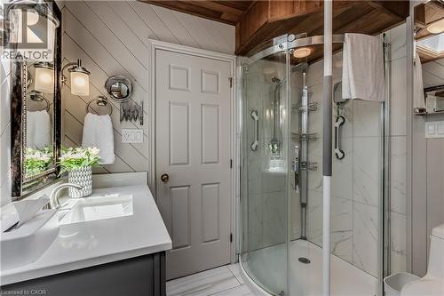 Bathroom featuring a curved glass shower enclosure, white marble-look wall tiling, and a dark wood-finish ceiling - 569 Locust Street, Burlington, ON - Indoor Photo Showing Bathroom