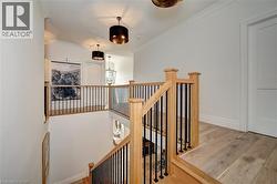 Hardwood flooring extending throughout a spacious landing with natural wood railings and black metal balusters - 