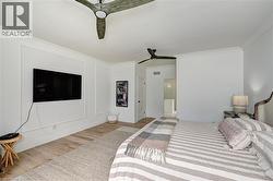Bright interior space featuring light wood-finish flooring, white crown molding, and two ceiling fans - 