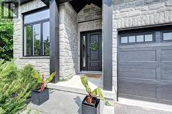Stone facade entrance featuring a dark wood-paneled door with transom window, modern black-framed windows, and an integrated garage with upper window panels - 