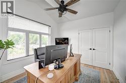 Vaulted ceiling room featuring a ceiling fan with wood-finish blades, a multi-pane window with horizontal blinds, wood-finish flooring, and white double doors with black hardware - 