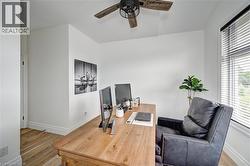 Bright interior space featuring wood-finish flooring, a contemporary ceiling fan, white baseboards, and a window with blinds - 