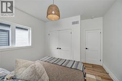 Bright room featuring wood-finish flooring, a contemporary woven pendant light fixture, and a window with horizontal blinds - 