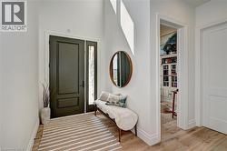 Entryway featuring a dark paneled door with a sidelight, high ceilings, and wood-finish flooring - 