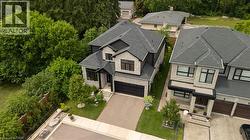 Modern two-story residence featuring a dark gray shingled roof, stone and dark siding exterior, black-framed windows, an attached two-car garage, and a paved driveway - 