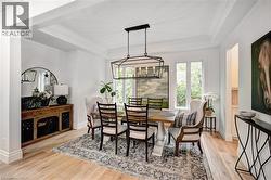 Formal dining area featuring a tray ceiling with crown molding, light wood-finish flooring, and a contemporary chandelier - 