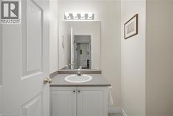 Vanity with an integrated sink, a gray countertop, white base cabinetry with brushed nickel hardware, and an overhead four-bulb light fixture - 