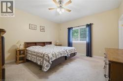 Carpeted room featuring a ceiling fan, a window with horizontal blinds, and a built-in wooden headboard - 