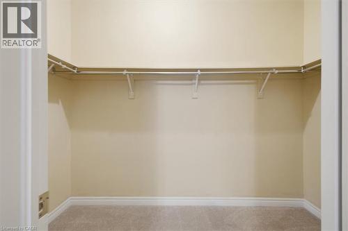 Walk-in closet with carpet flooring, light-toned walls, and a multi-section hanging rod system - 34 Southbrook Drive Unit# 13, Binbrook, ON - Indoor With Storage