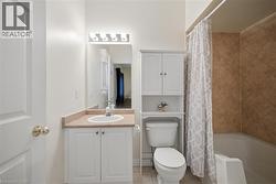 Bathroom featuring a white vanity with a single basin sink, light-colored countertop, and mirrored medicine cabinet - 