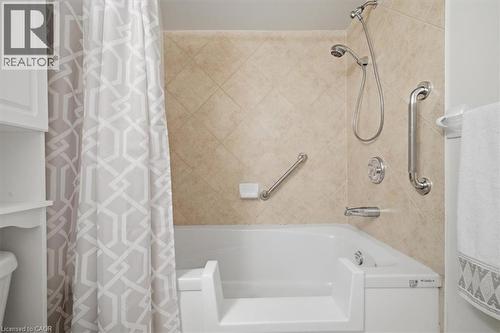 Walk-in tub with textured tile surround, chrome fixtures, and built-in grab bars - 34 Southbrook Drive Unit# 13, Binbrook, ON - Indoor Photo Showing Bathroom