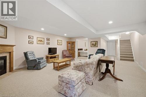 Carpeted living area featuring a built-in fireplace with a stone surround and wood mantle, recessed lighting, and a carpeted staircase - 34 Southbrook Drive Unit# 13, Binbrook, ON - Indoor With Fireplace