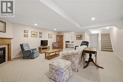Carpeted living area featuring a built-in fireplace with a stone surround and wood mantle, recessed lighting, and a carpeted staircase - 