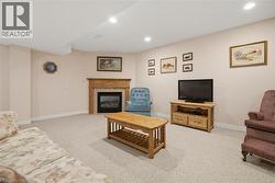 Recessed lighting illuminates a carpeted room featuring a fireplace with a wood mantel and stone surround - 