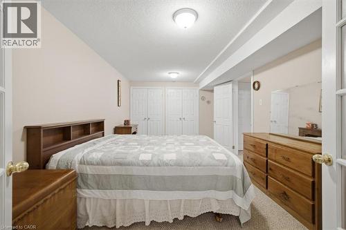 Carpeted room with a partial vaulted ceiling, featuring a pair of bifold closet doors, a single hinged door, and overhead flush-mount lighting fixtures - 34 Southbrook Drive Unit# 13, Binbrook, ON - Indoor Photo Showing Bedroom