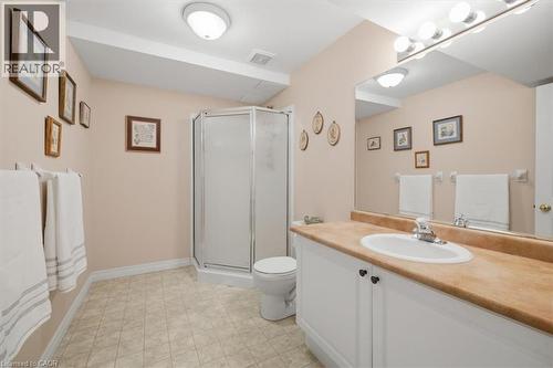 Bathroom featuring a corner shower enclosure, a vanity with a white basin and light-colored countertop, and square tile flooring - 34 Southbrook Drive Unit# 13, Binbrook, ON - Indoor Photo Showing Bathroom