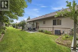 Expansive backyard featuring a stone patio, manicured lawn, and mature perimeter trees - 
