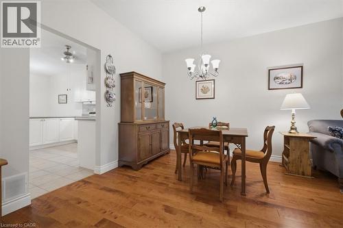 Dining area with wood-finish flooring, a five-light chandelier, and an arched entryway leading to the kitchen - 34 Southbrook Drive Unit# 13, Binbrook, ON - Indoor Photo Showing Dining Room