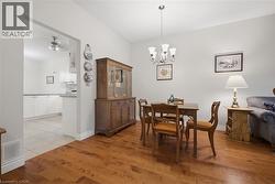 Dining area with wood-finish flooring, a five-light chandelier, and an arched entryway leading to the kitchen - 