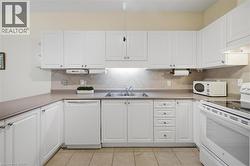 U-shaped kitchen featuring white cabinetry, light-toned countertops, a tile backsplash, and light beige floor tiles - 