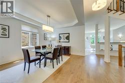 Open-concept dining area featuring hardwood flooring, a contemporary linear chandelier, and tray ceiling detail - 