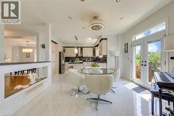 Bright eat-in kitchen area featuring white marble-look tile flooring, a contemporary ceiling fixture, recessed lighting, and double glass-paneled doors with transom windows - 