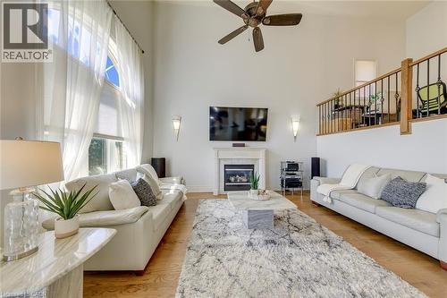 Vaulted ceiling living room featuring a gas fireplace with a mantel, wood-finish flooring, and a second-story interior balcony with wrought iron railing - 2380 Woodcrest Drive, Oakville, ON - Indoor Photo Showing Living Room With Fireplace