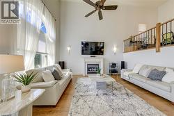 Vaulted ceiling living room featuring a gas fireplace with a mantel, wood-finish flooring, and a second-story interior balcony with wrought iron railing - 