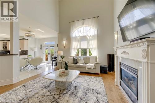 Living area featuring a tall arched window, hardwood flooring, and a decorative fireplace with a mantel - 2380 Woodcrest Drive, Oakville, ON - Indoor Photo Showing Living Room With Fireplace