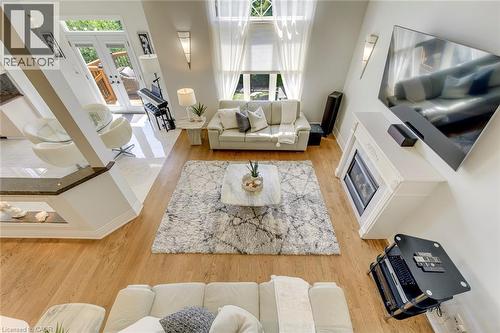 Two-story living area with hardwood flooring, a white mantel fireplace, and high windows featuring sheer drapery - 2380 Woodcrest Drive, Oakville, ON - Indoor