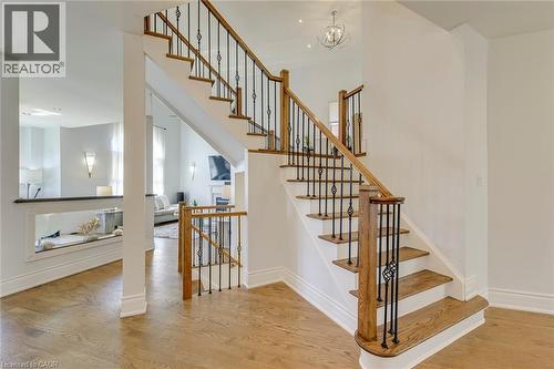 Hardwood flooring throughout the entry, featuring a custom staircase with wrought iron spindles and wood handrails - 2380 Woodcrest Drive, Oakville, ON - Indoor Photo Showing Other Room
