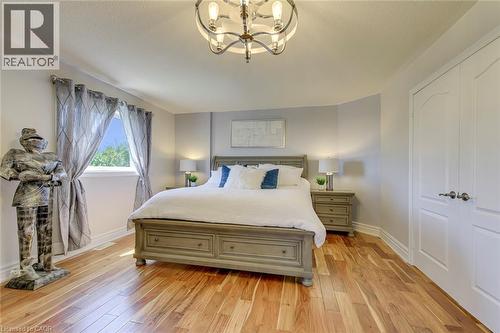 Hardwood flooring throughout featuring a ceiling-mounted light fixture, white trim, and a window with natural light - 2380 Woodcrest Drive, Oakville, ON - Indoor Photo Showing Bedroom