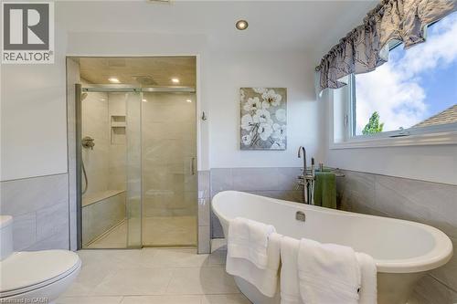 Bathroom featuring a freestanding soaking tub, a walk-in shower with a built-in bench, and a large window - 2380 Woodcrest Drive, Oakville, ON - Indoor Photo Showing Bathroom