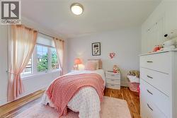 Bedroom featuring wood-finish flooring and a multi-pane window with white trim - 