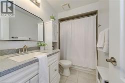 Bathroom with a white vanity featuring a light speckled countertop, an undermount sink, and brushed nickel hardware - 