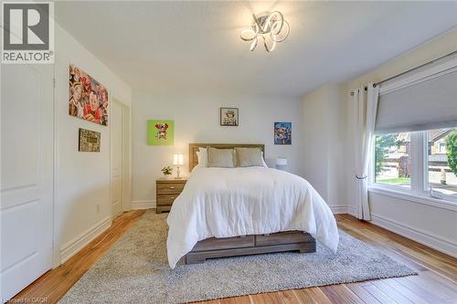 Bright room featuring wood-finish flooring, white trim, and a contemporary ceiling fixture - 2380 Woodcrest Drive, Oakville, ON - Indoor Photo Showing Bedroom