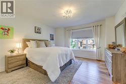 Bedroom featuring a large window, hardwood flooring, and a modern ceiling light fixture - 