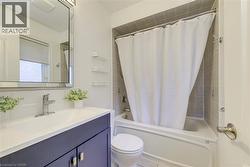Bathroom featuring a vanity with a dark blue cabinet and white countertop, chrome faucet, and a framed mirror - 