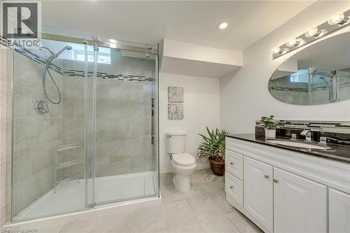 Full bathroom with a glass-enclosed shower featuring light-toned tilework and a decorative accent band - 2380 Woodcrest Drive, Oakville, ON - Indoor Photo Showing Bathroom