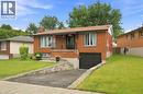 Brick exterior featuring a front balcony with black railing, an attached garage, a paved driveway, and a front lawn with stone retaining walls - 15 Quay Court, Hamilton, ON  - Outdoor 