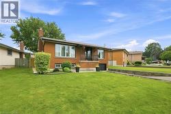 Brick exterior featuring a front balcony with black railing, integrated garage, and a large front lawn - 