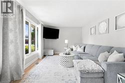 Bright living space featuring expansive windows, light wood-finish flooring, and neutral wall tones - 