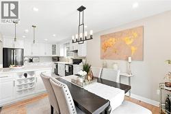 Open-concept kitchen and dining area featuring white shaker cabinetry, light-toned countertops, and wood-finish flooring - 