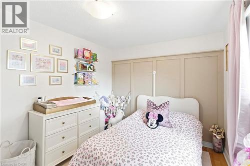 Light-filled room featuring a paneled accent wall, wood-finish flooring, and a flush-mount ceiling light - 15 Quay Court, Hamilton, ON - Indoor Photo Showing Bedroom