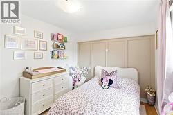 Light-filled room featuring a paneled accent wall, wood-finish flooring, and a flush-mount ceiling light - 